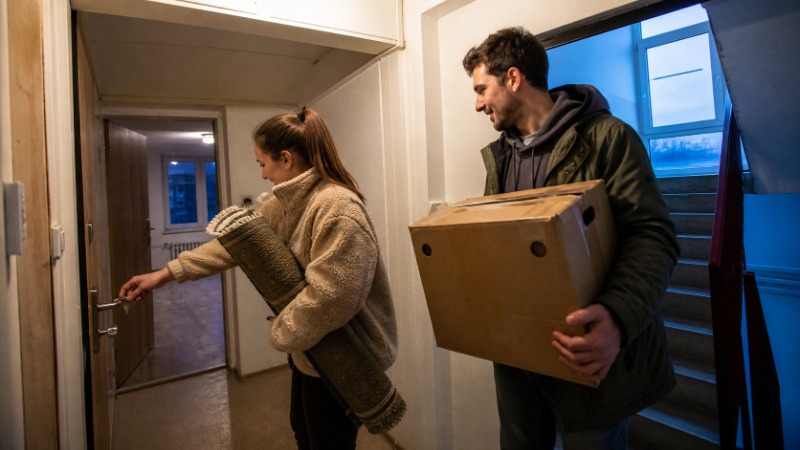 Mladý pár ve vlastním prvním bytě prochází papíry k hypotéce a počítá, kolik vlastních peněz na akontaci potřebují.